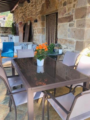 a dining room table with white chairs and a stone wall at Casa Mi Capricho in Concejero