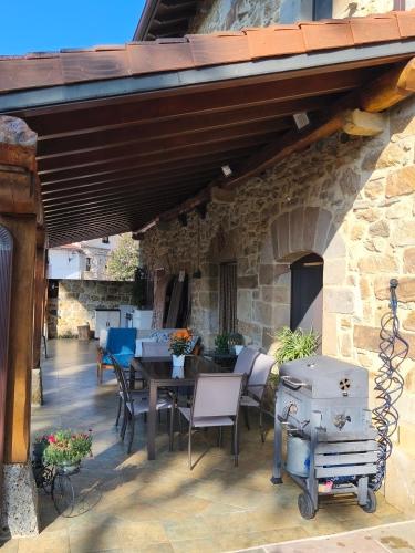 a patio with a table and chairs and a stone building at Casa Mi Capricho in Concejero