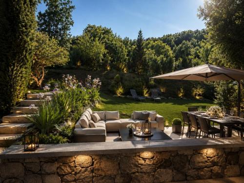 a garden with a couch and tables and an umbrella at Chalet Greystone in Brides-les-Bains