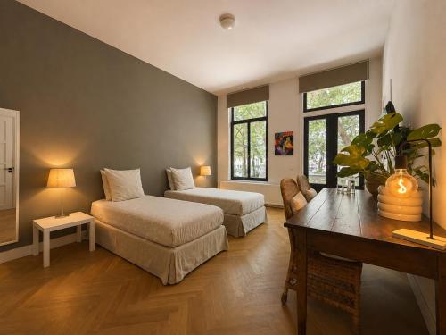 a bedroom with two beds and a table and a desk at Oranjepark in Dordrecht