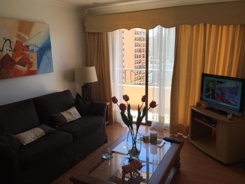 sala de estar con sofá y mesa con flores. en Apartamento Edificio Genova, en Viña del Mar