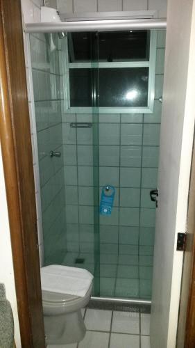 a bathroom with a toilet and a glass shower at Apart Hotel Quartier Latin in Vitória