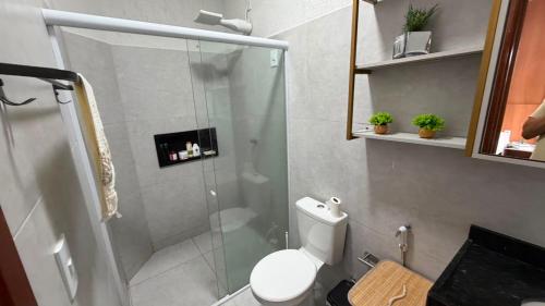 a bathroom with a toilet and a glass shower at Residencial Ibiapaba FLAT 31 - com piscina e ótima localização in Camocim