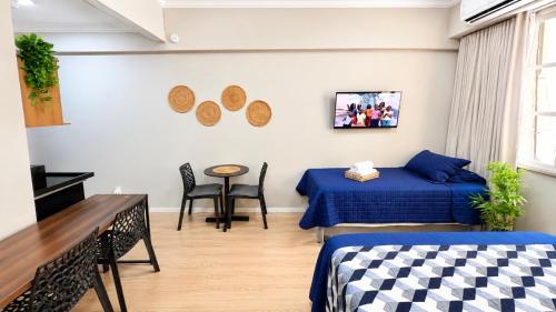 a room with two beds and a table and chairs at Flat Premium a 500m do aeroporto Santos Dumont & Consulados in Rio de Janeiro