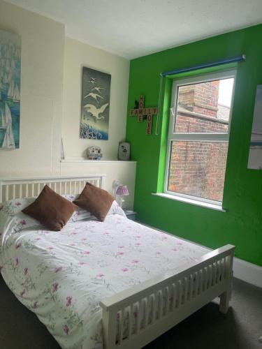 a green bedroom with a bed and a window at Henry's On The Prom in Great Yarmouth