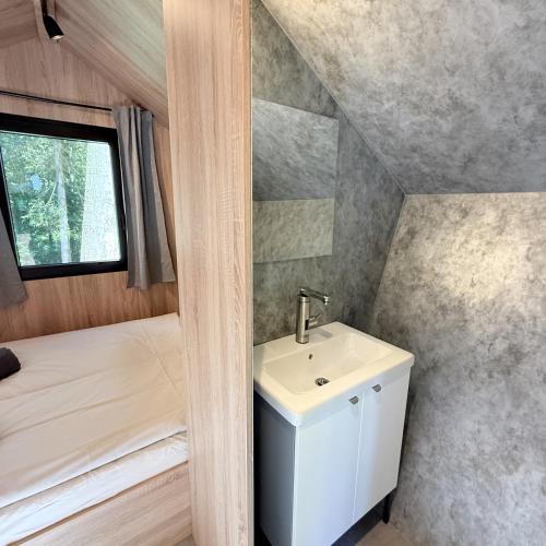 a small bathroom with a sink and a bed at Glamping chatky in Spišské Tomášovce