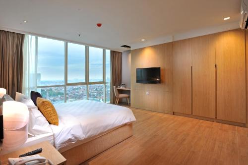 a hotel room with a bed and a television at Midtown Residence Surabaya in Surabaya