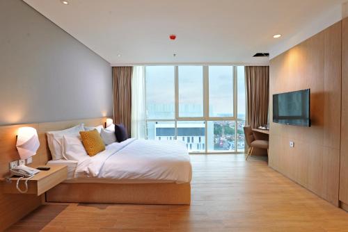 a hotel room with a bed and a television at Midtown Residence Surabaya in Surabaya