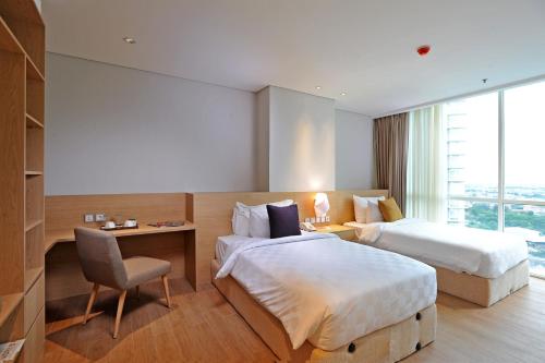 a hotel room with two beds and a desk at Midtown Residence Surabaya in Surabaya