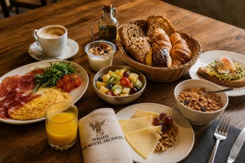 a wooden table topped with plates of breakfast food at Posada San Miguel Arcángel Experience in Arévalo