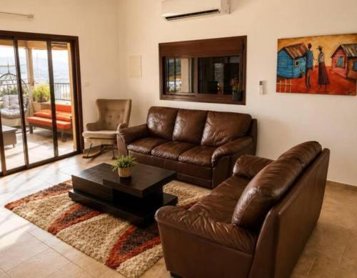 a living room with a leather couch and a table at Art & View Family Jacuzzi Suite with Balcony in Maghār