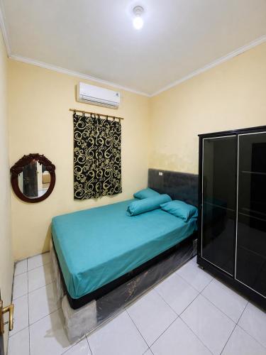 a bedroom with a blue bed and a mirror at Guest House Brahu Syariah in Trowulan