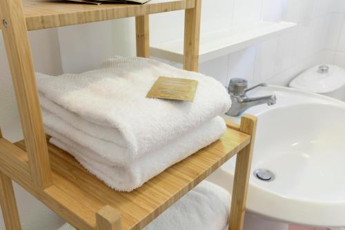 a pile of white towels on a shelf next to a sink at Residence delle Nazioni - Spiaggia privata su richiesta in Principina a Mare