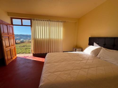 a bedroom with a bed and a large window at Casa Cóndor Ausangate in Tinke