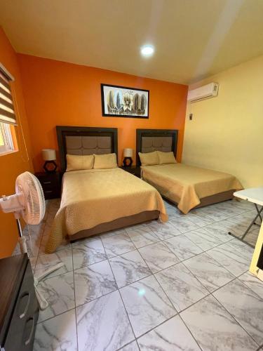 two beds in a room with orange walls at Hotel Santa Cecilia in Villa Corona