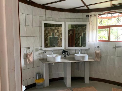 a bathroom with two sinks and two mirrors at Amitie Chalets Praslin in Grand Anse
