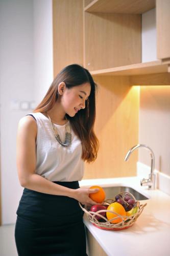 a woman standing in a kitchen with a basket of fruit at Midtown Residence Surabaya in Surabaya