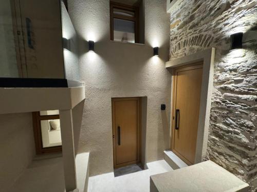 a hallway with two doors and a stone wall at Divine Suites Tinos in Tinos