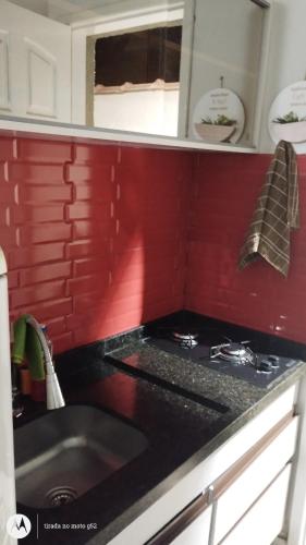 a kitchen with a stove and a red wall at Loft Essence in Volta Redonda