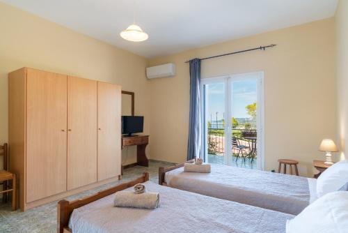 a bedroom with two beds and a sliding glass door at Maria Anastasia Studios in Trapezaki