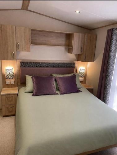 a bedroom with a large bed with purple pillows at Sunset View - with view of the lighthouse and a shower and bath in Lossiemouth