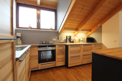 a kitchen with wooden cabinets and a stove top oven at Kelchalm Superior Spacious Mountain Apartment in Bad Kleinkirchheim