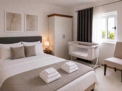 a white bedroom with a bed and a chair at Villa Conceptt casa in Jasenak