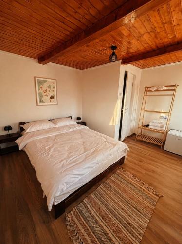 a large bed in a bedroom with a wooden ceiling at Cabanele din livadă in Corbi