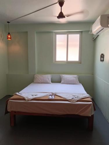 a bed in a room with a ceiling fan at Relax Residency in Mandapam