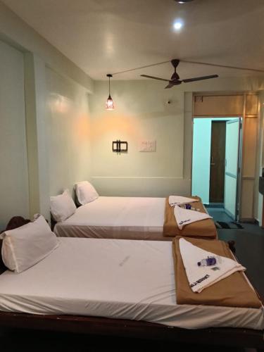 two beds in a bedroom with a ceiling fan at Relax Residency in Mandapam