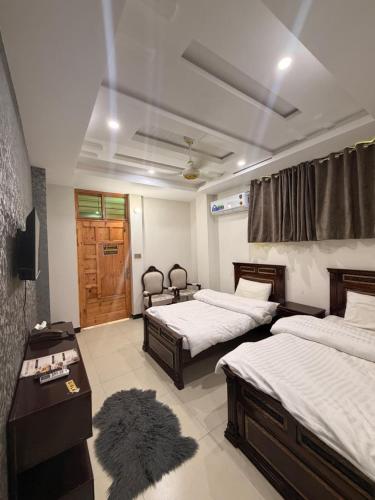 a bedroom with two beds and a desk and a door at The Canvas Hotel in Abbottabad