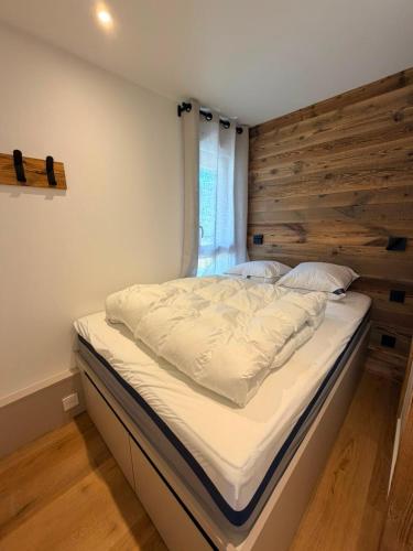 a large bed in a room with a wooden wall at Le 400 BIS in Bourg-Saint-Maurice