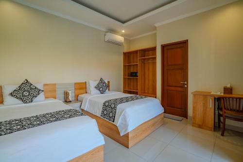 a bedroom with two beds and a wooden door at Canggu Bagus Guest House in Canggu