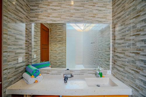 a bathroom with a sink and a large mirror at Canggu Bagus Guest House in Canggu