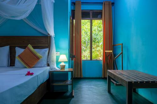 a bedroom with a bed and a table and a window at Sigiri Siesta Homestay in Sigiriya