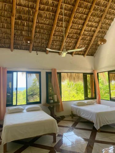two beds in a room with large windows at Villa del Mar in Zipolite