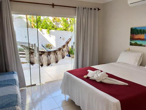 a bedroom with a bed and a large window at Pousada Caliandra Pipa in Pipa