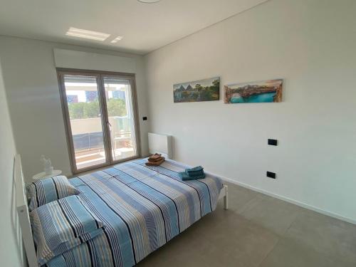 a white bedroom with a bed and a window at Brezza di Bari, Terrace & Free Parking, family and group apartment by Leviora Collection in Bari