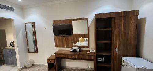 a hotel room with a desk and a television at فندق دار المتكاملة 4 in Al Khansāk