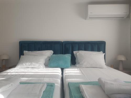 a large bed with a blue headboard and white pillows at Apartmani Zoka in Niš