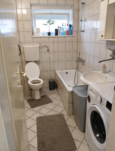 a bathroom with a toilet and a sink and a washing machine at Apartman Čeliković centar Šamca, parking, balkon, WiFi in Bosanski Šamac