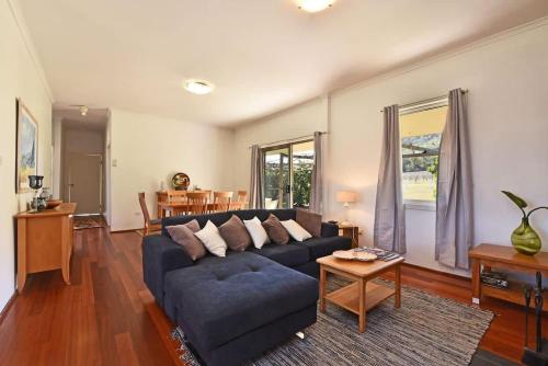 a living room with a blue couch and a table at Somerville Wine Cottage Hideaway 3-Bedroom Cottage Near Broke Wineries in Broke