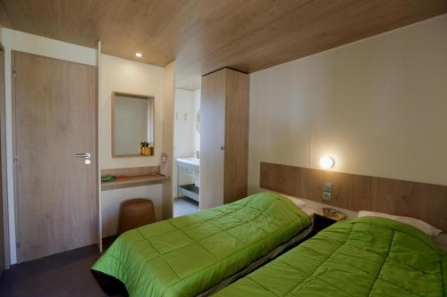 a bedroom with a green bed and a bathroom at Camping le Dolmen, Carnac, Morbihan in Carnac