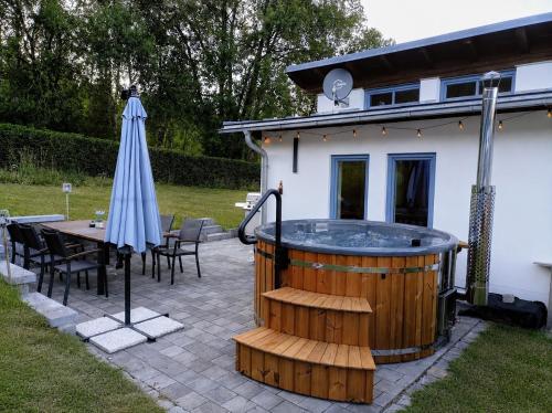 a hot tub in a backyard with a table and an umbrella at Haus im Grünen l Hot Tub l aktivCARD inklusive in Regen