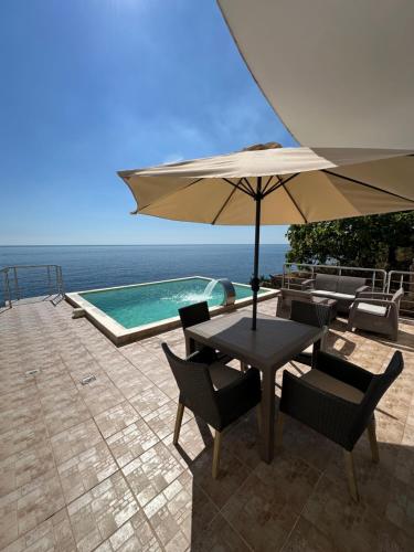 a table with an umbrella next to a swimming pool at Villa Bakic in Dobra Voda