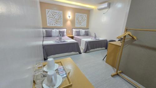 a room with two beds and a table in a room at La Casa Princesa Inn in Puerto Princesa City