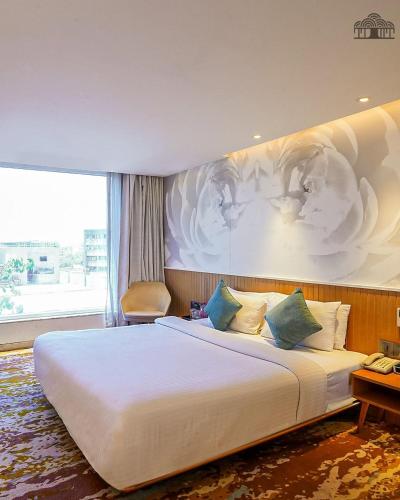 a bedroom with a large white bed with a painting on the wall at The Atlantiis Suites Nr Vishwanath Temple in Varanasi