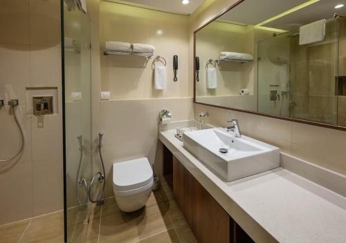 a bathroom with a sink and a toilet and a shower at The Atlantiis Suites Nr Vishwanath Temple in Varanasi