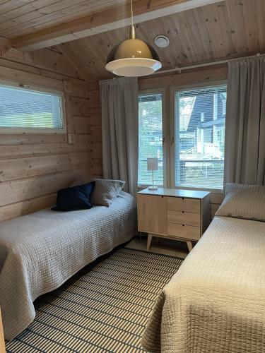 a bedroom with two beds and a desk and a window at Villa Loiste Himos Chalet with Hot Tub in Jämsä