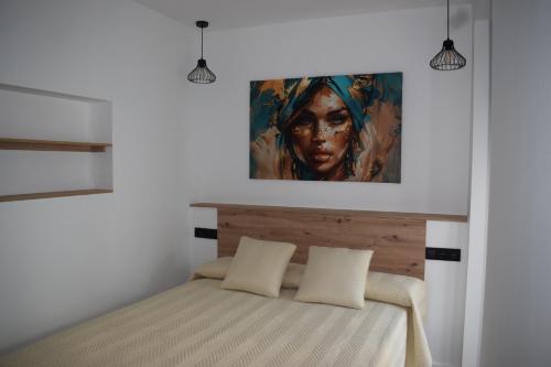 a bedroom with a bed with a painting on the wall at El patio de Carmen in Hornachuelos